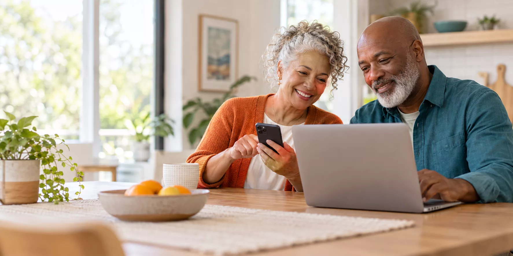Two active adults using a smartphone and laptop together at home